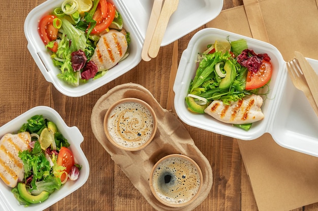 Salade fraîche de plats à emporter avec poulet grillé et café sur la vue de dessus de fond en bois