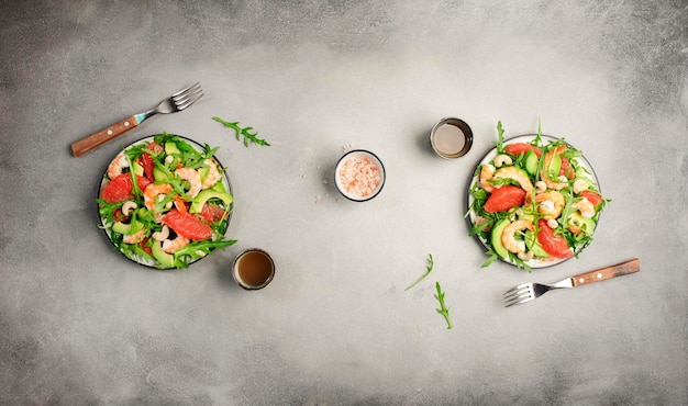 Salade fraîche saine aux crevettes avocat pamplemousse roquette et noix de cajou Table de cuisine en pierre grise Vue de dessus d'arrière-plan de la bannière