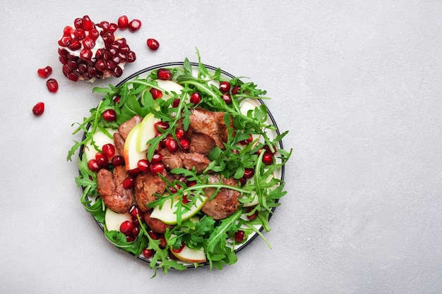 Salade fraîche saine avec foie de poulet pomme grenade et roquette Table de cuisine blanche vue de dessus