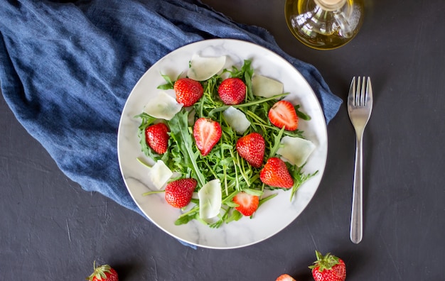 Salade de fraises, de roquette et de fromage sur fond sombre. Aliments diététiques.