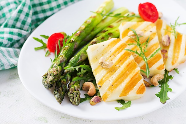 Salade de fromage halloumi grillé avec tomates et asperges sur plaque sur fond clair. Nourriture végétarienne saine.