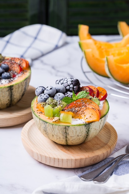 Salade de fruits au yaourt dans un bol de melon cantaloup sculpté