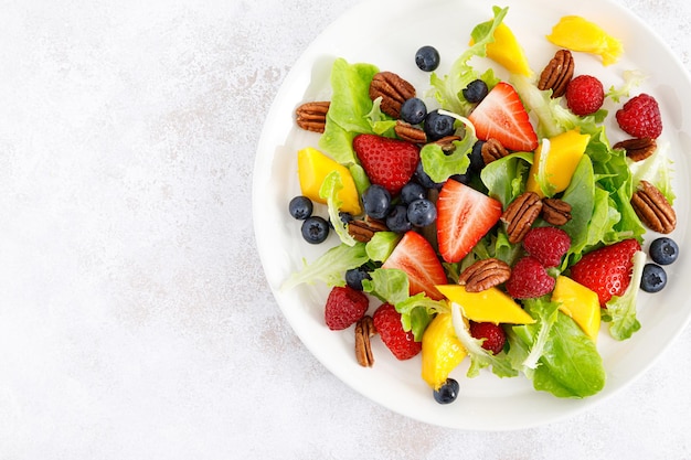 Salade de fruits et de baies avec fraise, myrtille, framboise, mangue et noix de pécan Régime alimentaire sain Vue de dessus