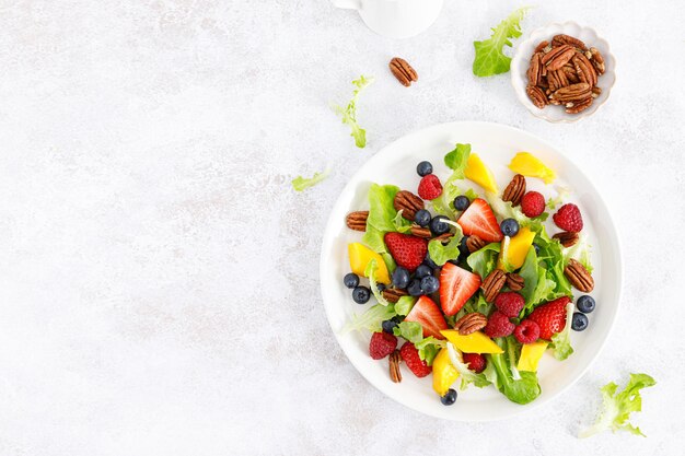 Salade de fruits et de baies avec fraise, myrtille, framboise, mangue et noix de pécan Régime alimentaire sain Vue de dessus