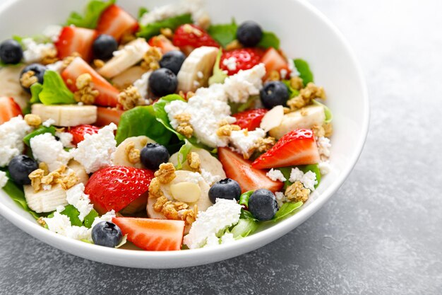 Salade de fruits et de baies avec fraises fraîches, myrtille, banane, fromage cottage et granola aux amandes Alimentation saine petit-déjeuner