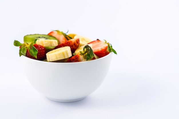 Une salade de fruits coupée dans un bol blanc, recette sympa et saine