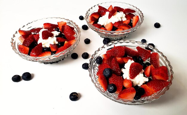 Photo salade de fruits avec de la crème fouettée sur fond blanc