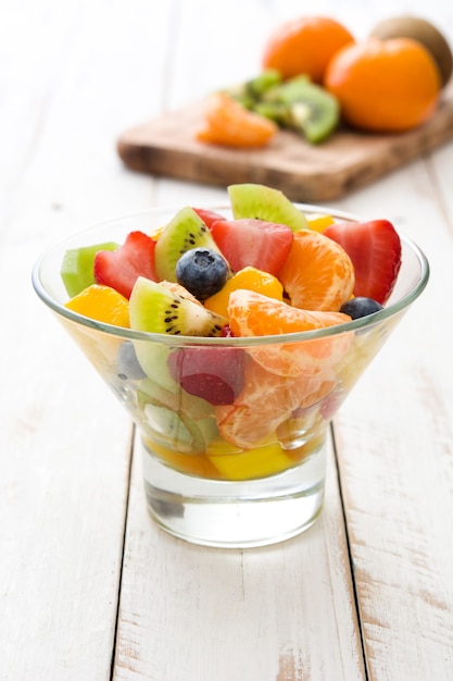 Salade de fruits dans un bol en cristal sur une table en bois blanc