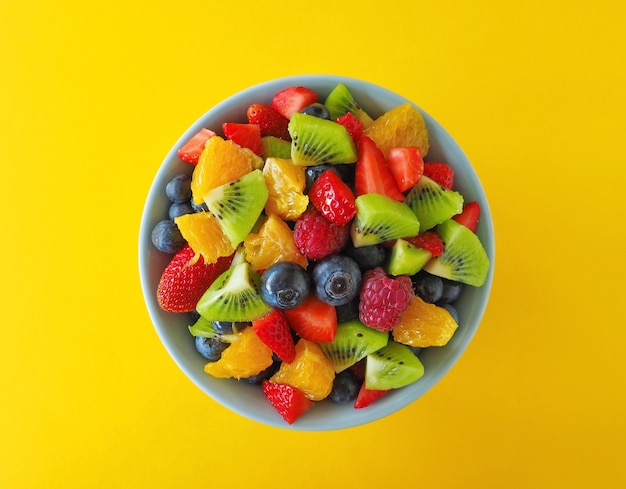 Salade de fruits dans un bol sur une surface jaune