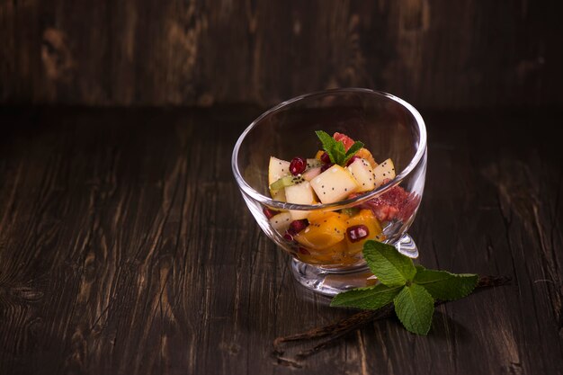 Salade de fruits dans des bols de verre sur fond sombre