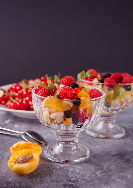 Salade de fruits frais et de baies sur un bol sur le fond en béton