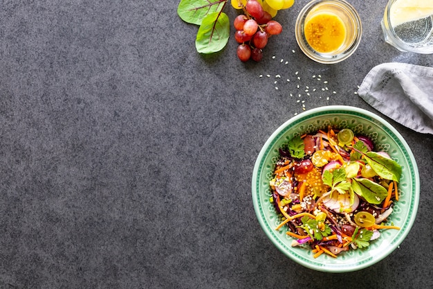 Salade de fruits et légumes frais dans une assiette sur une surface en pierre noire. Vue de dessus