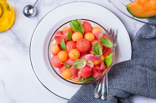 Salade de fruits avec melon cantaloup, pastèque et prosciutto dans un bol sur la table de la cuisine