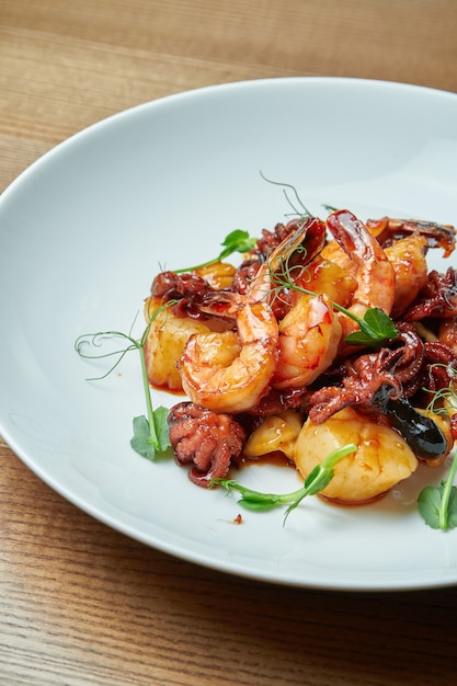 Salade de fruits de mer appétissante dans une sauce aigre-douce dans une assiette blanche. Salade de crevettes, poulpes, pétoncles et calmars