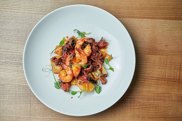 Salade de fruits de mer appétissante dans une sauce aigre-douce dans une assiette blanche. Salade de crevettes, poulpes, pétoncles et calmars