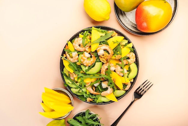 Salade de fruits de mer avec crevettes à la mangue et épinards aux noix d'avocat et roquette Vue de dessus fond rose