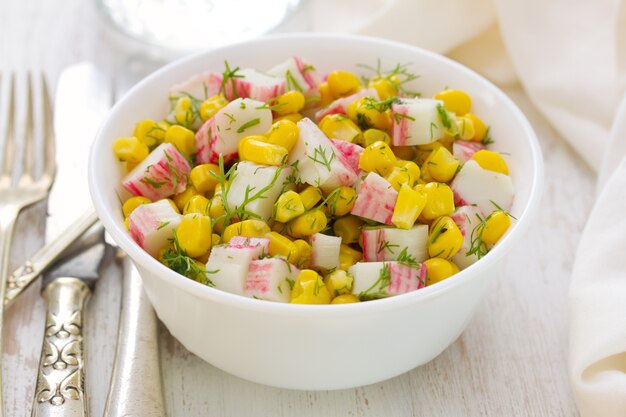 Salade de fruits de mer avec du maïs dans un bol blanc sur une table blanche