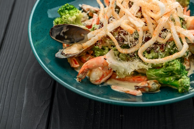 Salade de fruits de mer frais aux crevettes, moules et légumes sur fond noir