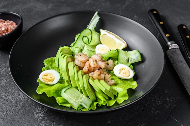 Salade de fruits de mer frais avec crevettes grillées, crevettes, œuf, avocat et concombre dans une assiette