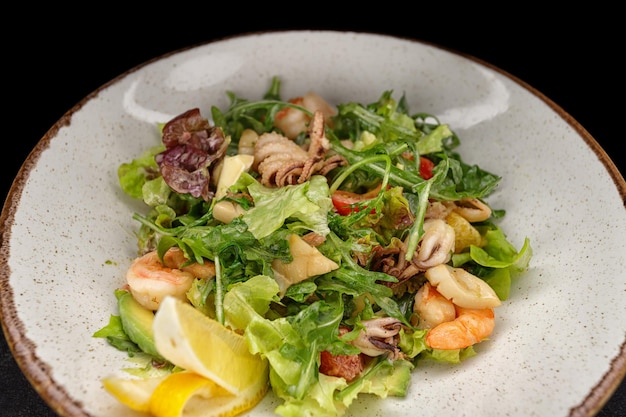 Salade de fruits de mer, pieuvre, crevettes, coquillages, calamars et légumes verts mélangés
