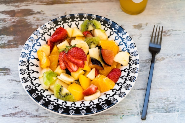 Photo salade de fruits naturels et sains à l'orange dans une assiette vintage, sur une surface rustique.