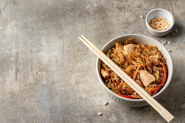 Salade Funchose au poulet et légumes dans un bol avec des baguettes en bois Cuisine asiatique