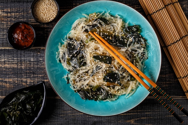 Salade Funchoza avec wakame sur fond sombre.