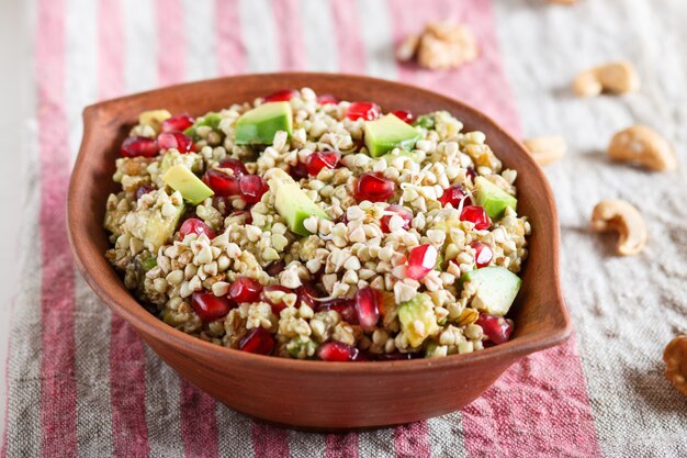 Salade de graines de noyer et de grenade avocat sarrasin germé en plaque d'argile sur fond de bois blanc