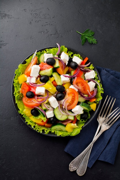 Salade grecque en assiette en céramique sur béton noir