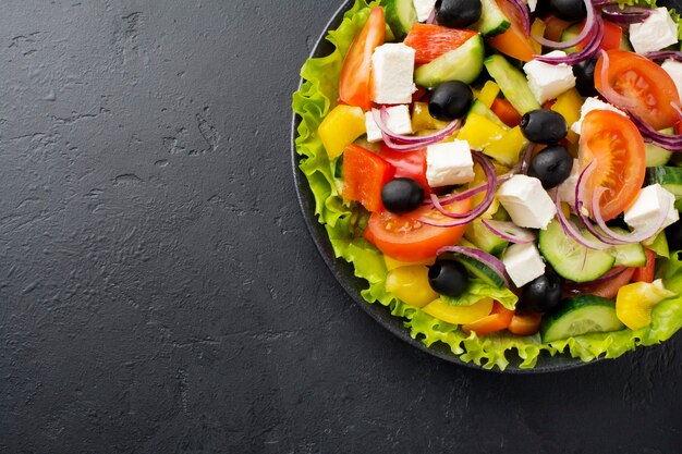 Salade grecque en assiette en céramique sur béton noir