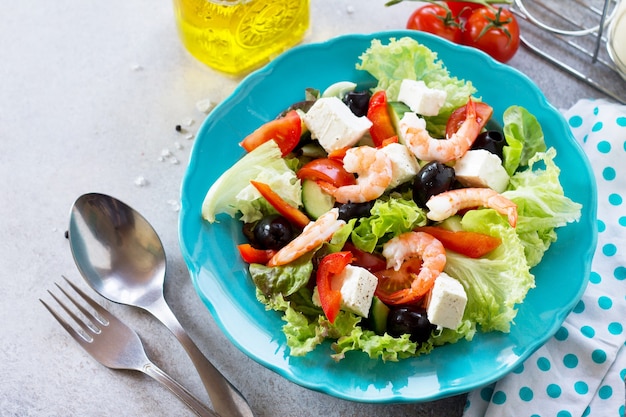 Salade grecque aux crevettes et légumes sur une table en pierre légère ou en ardoise