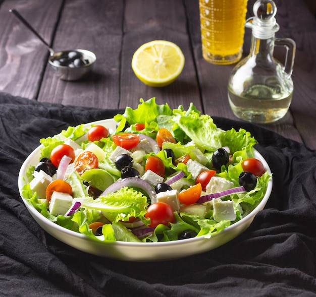 Photo salade grecque dans une assiette sur fond sombre. nourriture végétarienne saine. fromage feta, feuilles de laitue, tomates cerises.