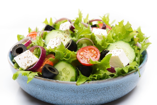 Photo salade grecque avec feta, olives, tomates et concombres isolés sur fond blanc, gros plan