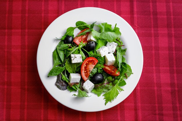 Salade grecque fraîche en plaque blanche sur fond rouge. gros plan et vue de dessus.