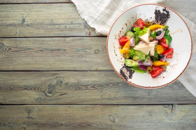 Salade grecque avec des légumes frais, fromage feta bouchent, fond en bois