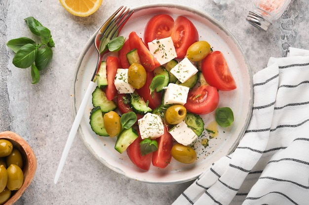 Salade grecque Salade grecque fraîche avec légumes frais tomate concombre olives vertes et fromage feta sur fond de table en béton gris ancien Vue de dessus