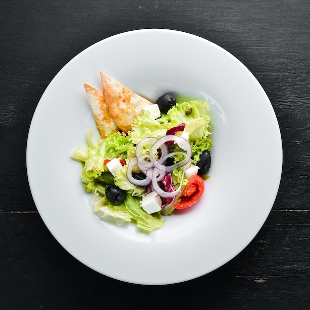 Salade grecque. Salade de légumes avec fromage feta, olives et tomates cerises. Dans l'assiette. Vue de dessus. Espace libre pour votre texte. Style rustique.