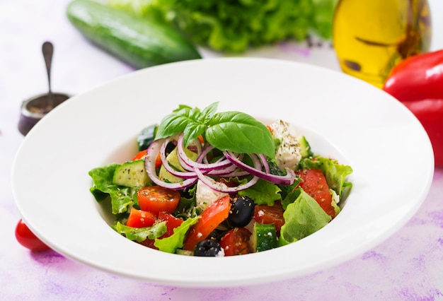 Salade grecque avec tomate fraîche, concombre, oignon rouge, basilic, laitue, fromage feta, olives noires et herbes italiennes