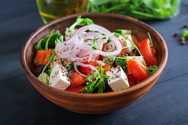 Salade grecque avec tomates fraîches, concombre, oignon rouge, basilic, fromage feta, olives noires et herbes italiennes