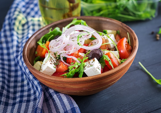 Photo salade grecque avec tomates fraîches, concombre, oignon rouge, basilic, fromage feta, olives noires et herbes italiennes