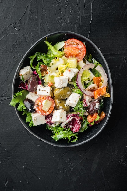 Salade grecque traditionnelle avec légumes frais, feta et olives, sur fond noir