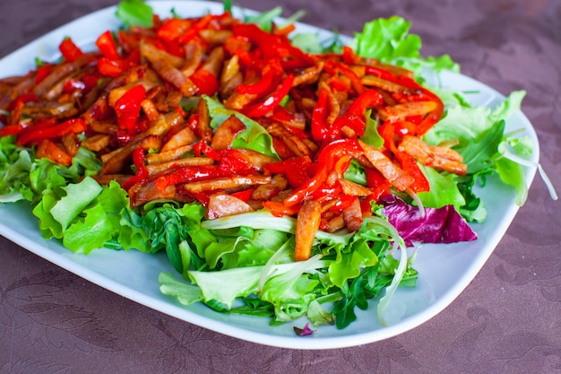 Salade hachée avec des poivrons, de la laitue et des tomates à la plaque blanche sur la table