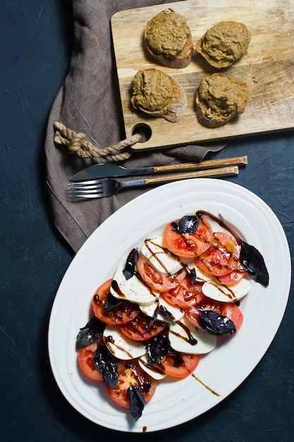 Salade italienne Caprese.Ingrédients fromage mozzarella, tomates, basilic, sel, poivre, balsamique.