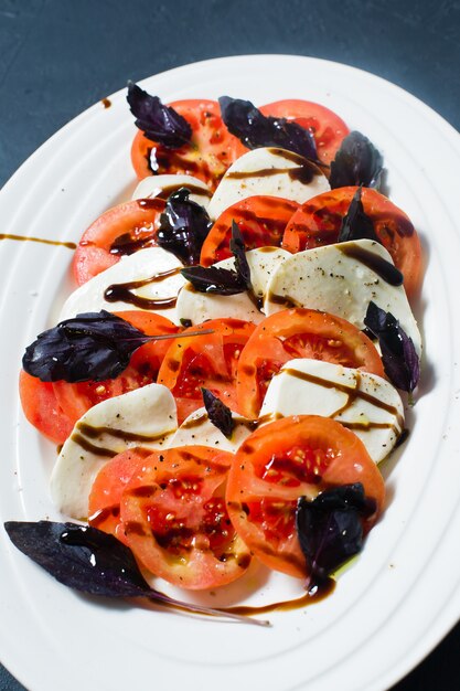 Salade italienne Caprese.Ingrédients fromage mozzarella, tomates, basilic, sel, poivre, balsamique.