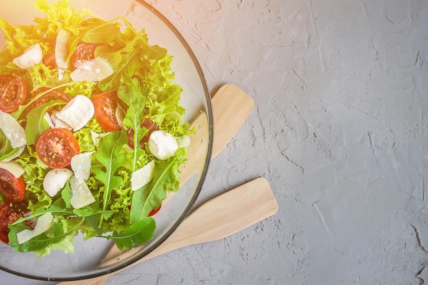 Salade italienne avec laitue et roquette dans un bol en verre sur fond de béton avec espace de copie