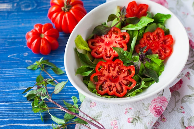 Salade italienne à la tomate dans un plat blanc sur table bleue