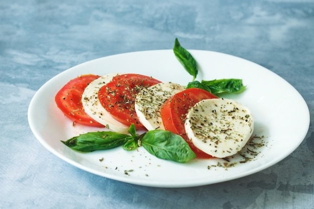 Salade italienne traditionnelle avec des tomates mûres fromage mozzarella avec des feuilles de basilic frais