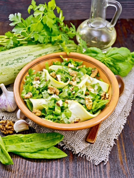 Salade de jeunes courgettes oseille ail et huile végétale assaisonnée de noix dans une assiette sur une serviette de sac sur fond de planche de bois