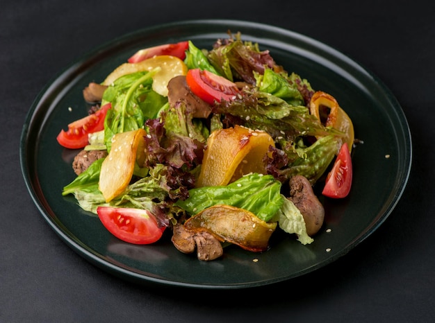 Salade de laitue au foie poires caramélisées et tomates sur fond sombre