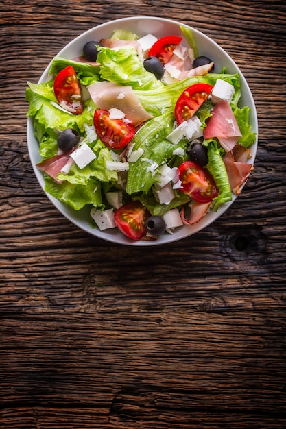 Salade de laitue fraîcheSalade méditerranéenne saine olives tomates fromage parmesan et prosciutto